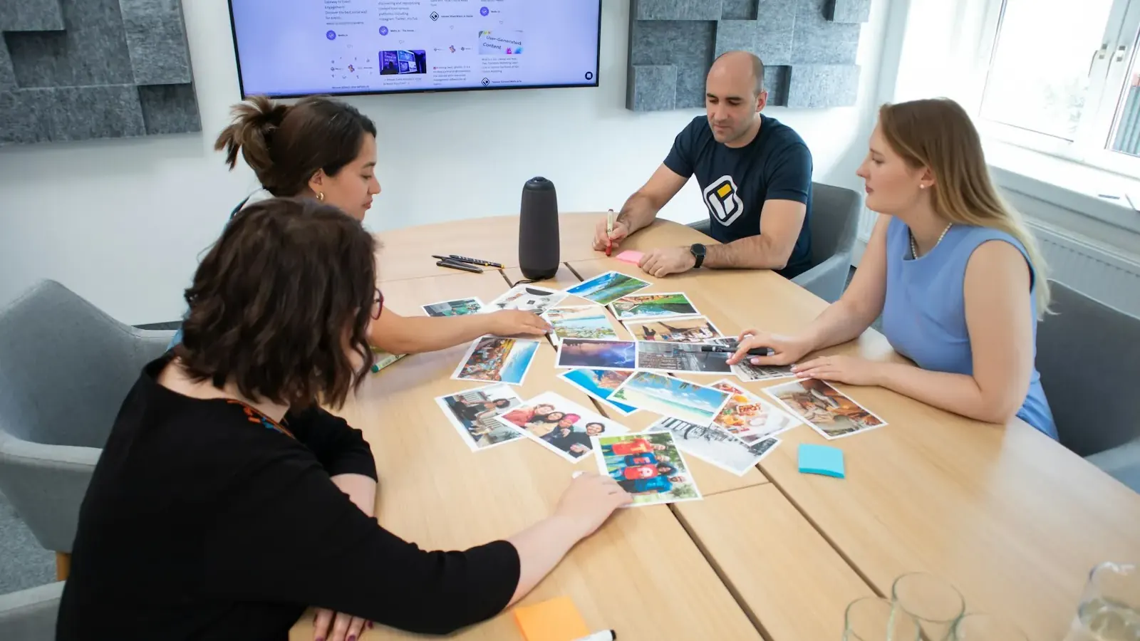 Ein Marketingteam legt ausgedruckte Anzeigenmotive auf einem Besprechungstisch aus.