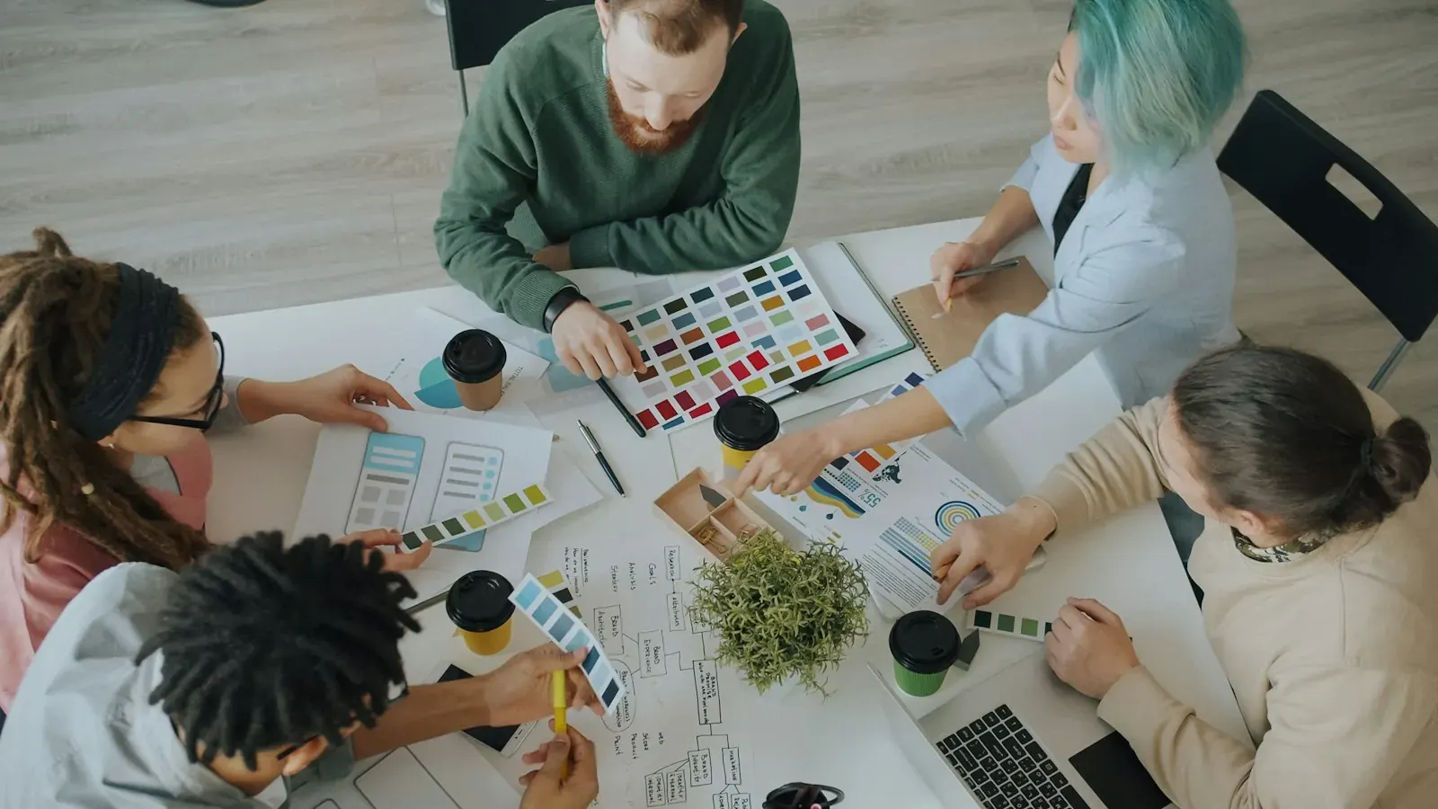 From above, a team picks a colour palette from swatches for a brand identity.