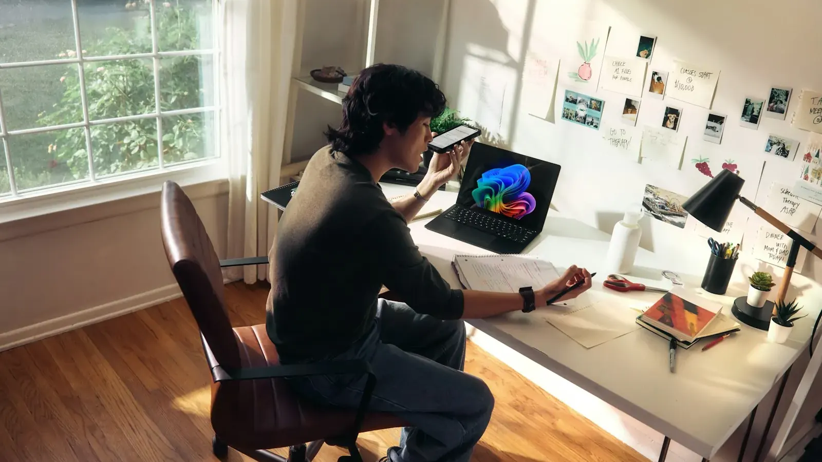 A man works on a laptop in a sunlit home office, researching AI answers.