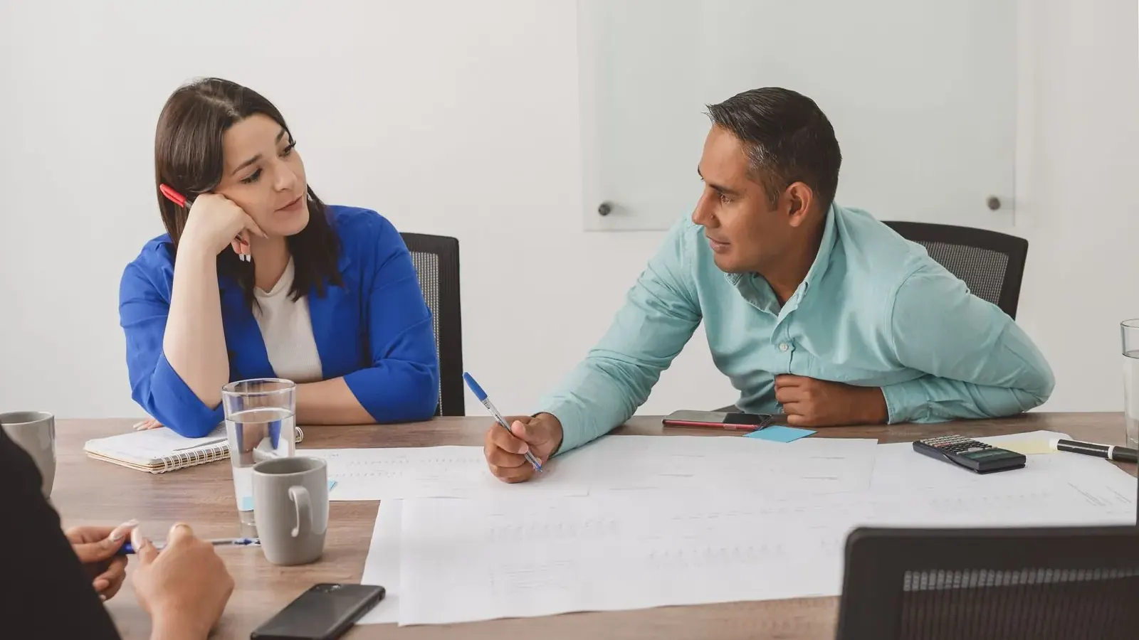 Una emprendedora y una consultora comentan unos documentos en una mesa de reuniones.