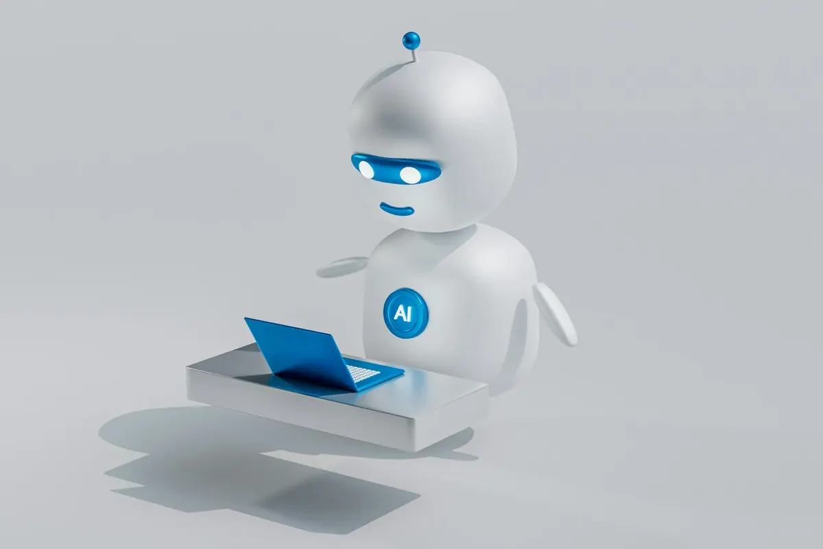 Un pequeño robot asistente blanco trabaja ante un portátil diminuto, como un ayudante de IA.
